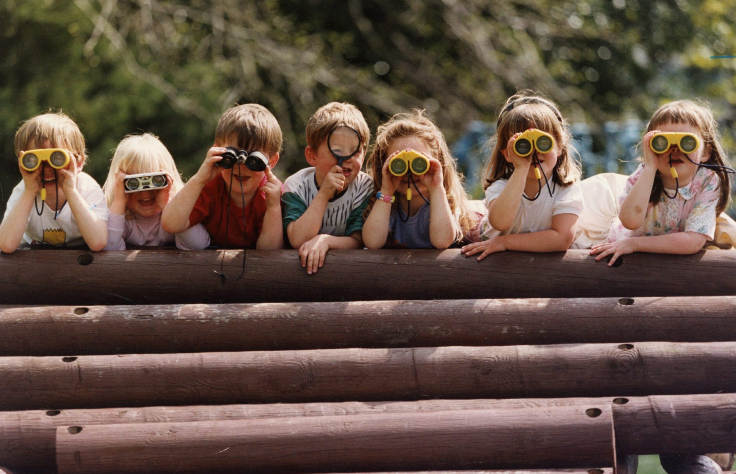 youngsters look through binoculars towards the camera