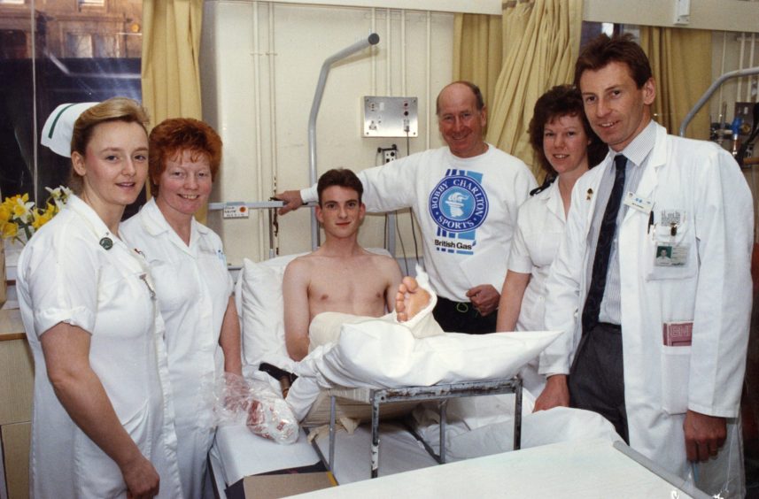 Bobby and hospital staff beside a hospital patient's bed