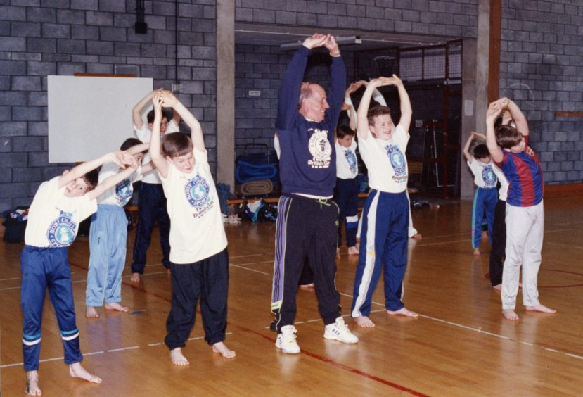 Bobby Charlton and some kids do stretches at the Gardyne with the karate class. 