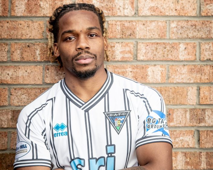 New Dunfermline Athletic FC signing Dapo Mebude stands in front of a brick wall.