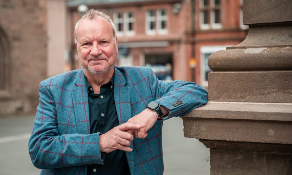 Pete Wishart in tweed jacket leaning against pillar