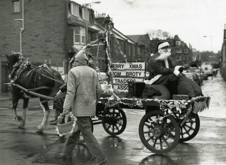 Santa Claus sits on the back of a horse-drawn cart as it makes its way through Broughty Ferry