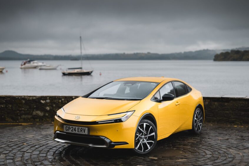 The Prius seen from the front and parked in front of a loch