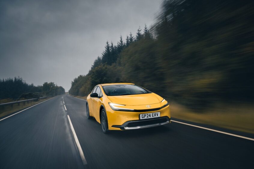 A yellow Prius on a forest road