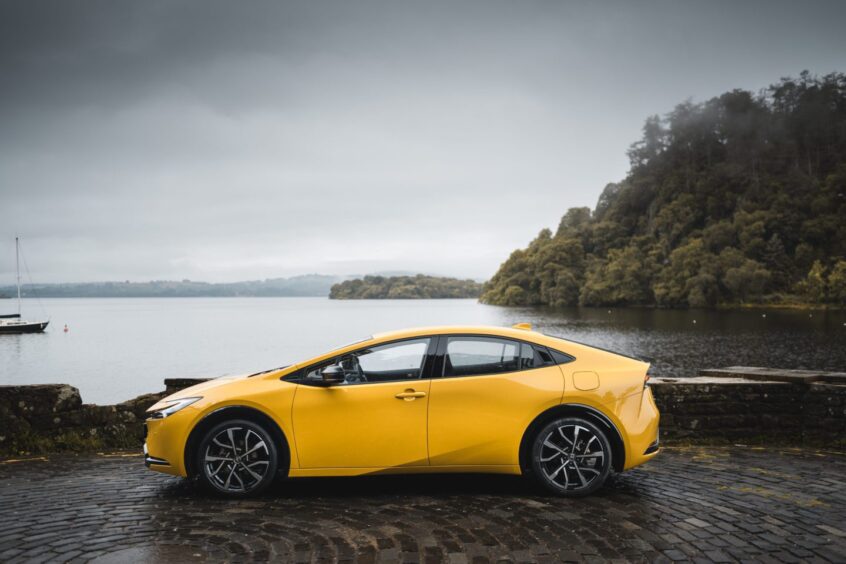 The Toyota Prius seen in profile in front of a loch.