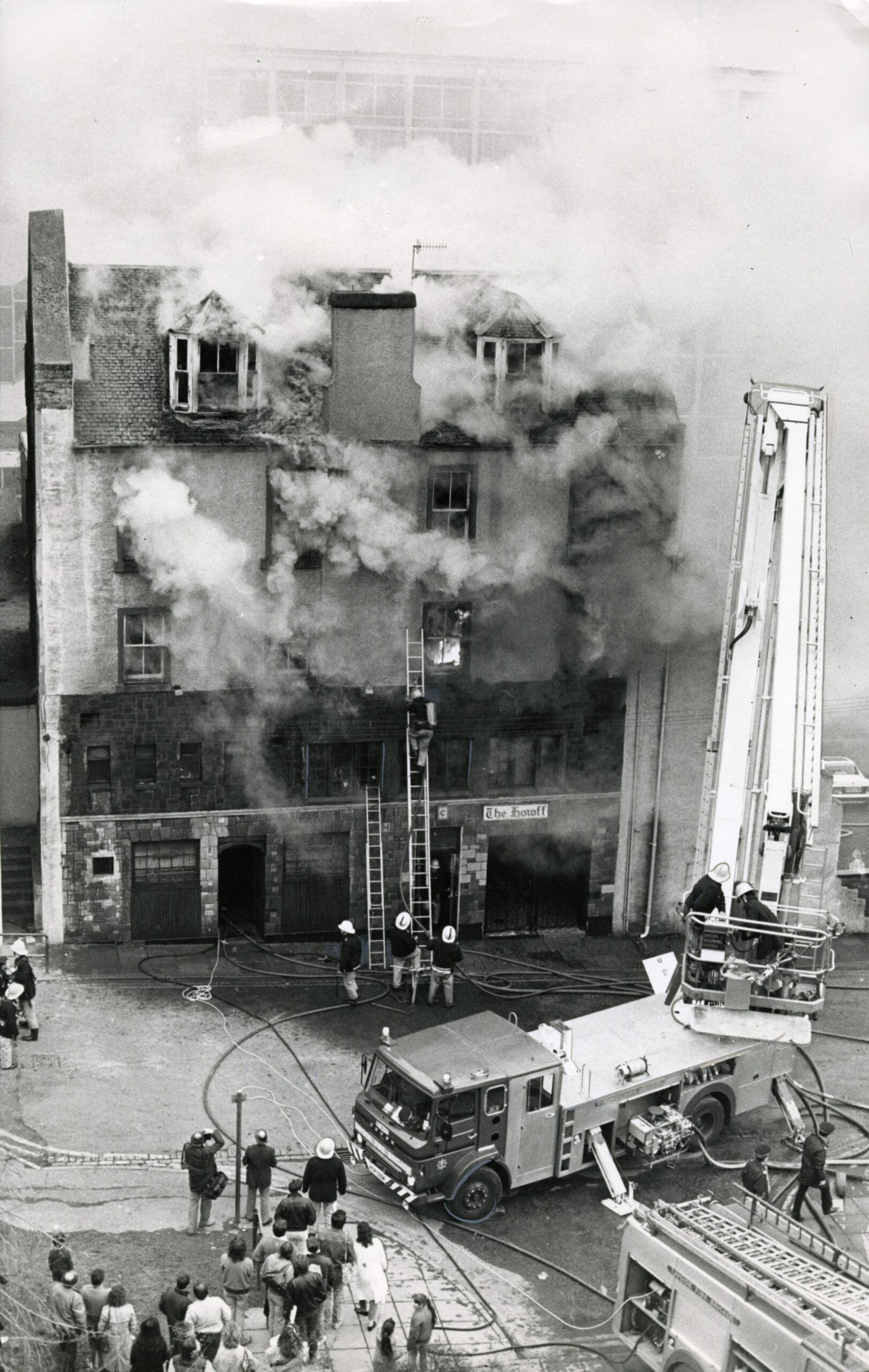 smoke pours out of the Bread while firefighters battle the blaze using ladders and an elevated platform