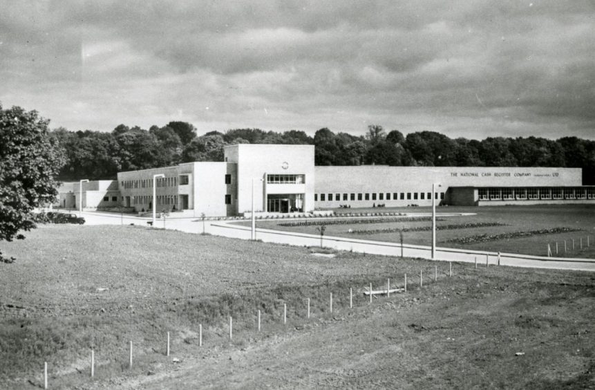 An exterior shot showing how the former NCR site looked in 1986, with grass areas in the foreground and trees in the distance