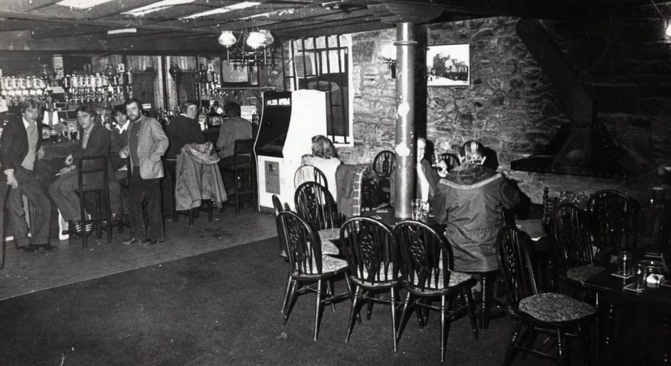 regulars stand by the bar and one man sits at a table in The Windmill Bar in the Hilltown in April 1982.