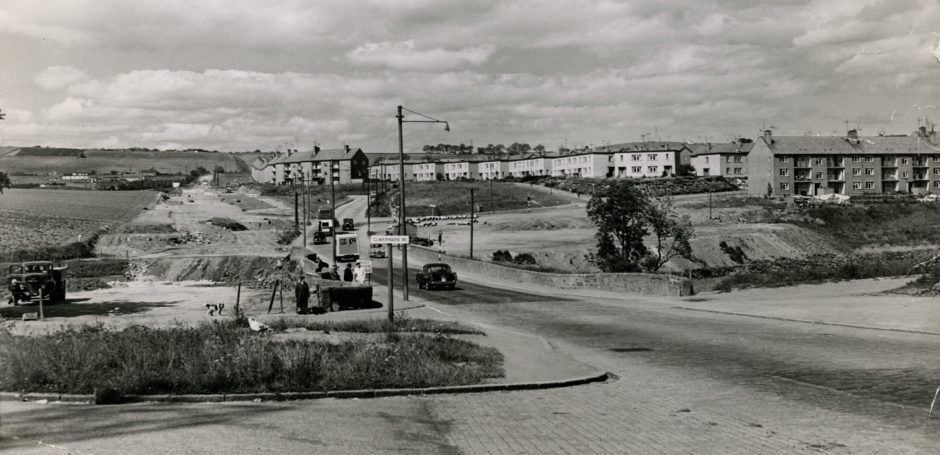 a road with some housing and fields showing how Fintry began taking shape from 1949 to 1960. 