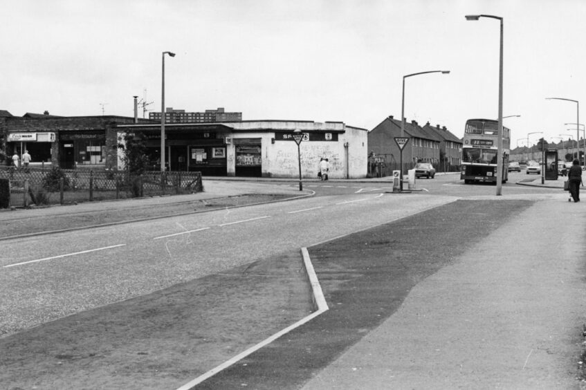 A 33 goes past some shops in 1980.