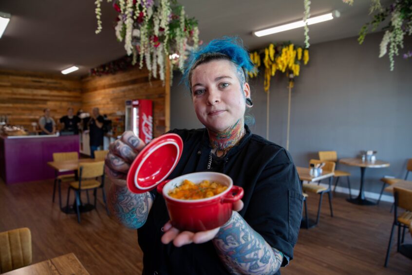 Jodiee Clark, chef, holds up a dish containing food 