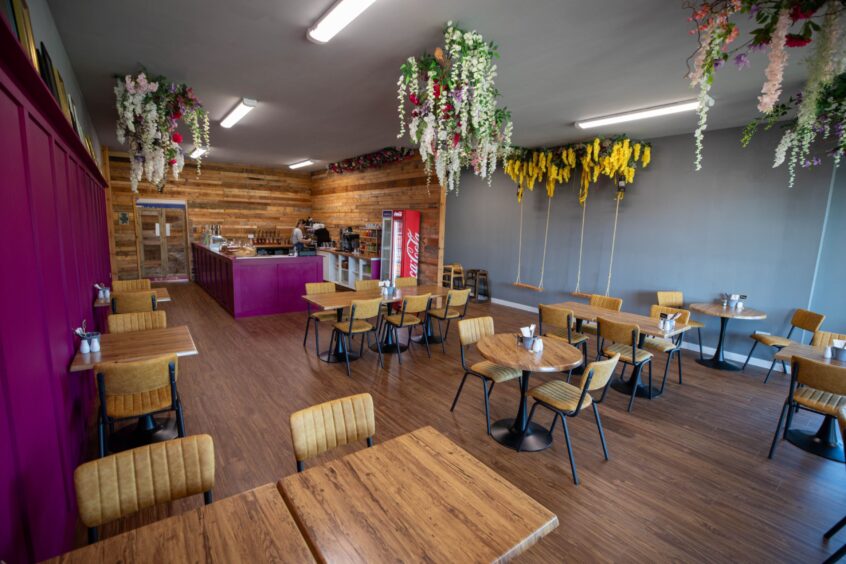 Tables and chairs sit amid bright colours and floral touches in the cafe