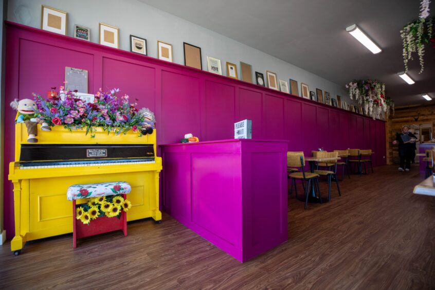 The colourful renovated interior of The Madhouse Bakery, Glenrothes, which includes a yellow piano and pink walls