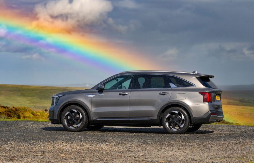 the car parked in a country layby with a rainbow over fields in the distance