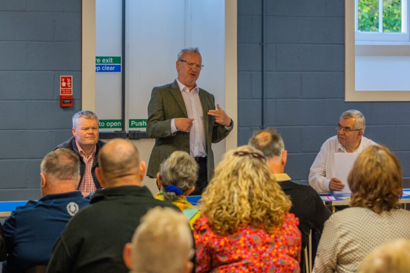 Pete Wishart MP talking to room, with two men on either side