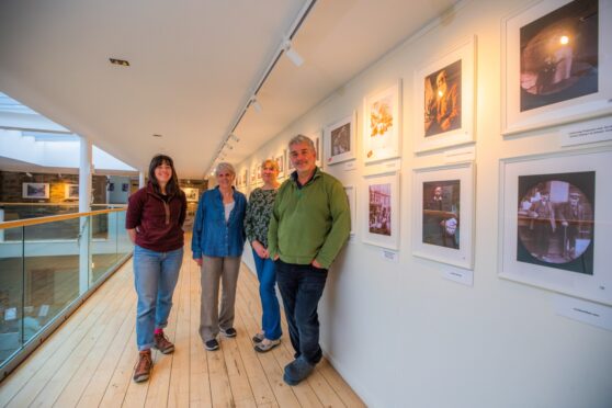 Four people standing in front of row of photos at Birnam Arts, Dunkeld