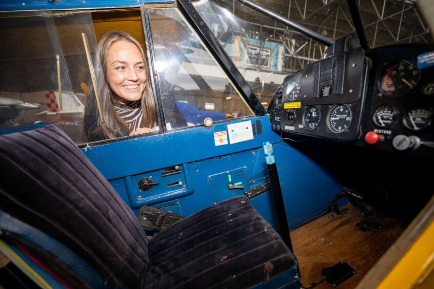 Woman looking inside window at control panel of plane inside hangar at Perth airport