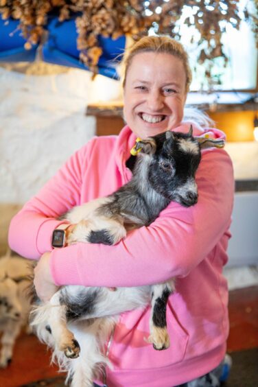 Debbie enjoys a cuddle with one of the younger pygmy goats during the Pilates class.