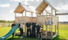 people standing in front of wooden climbing frame.