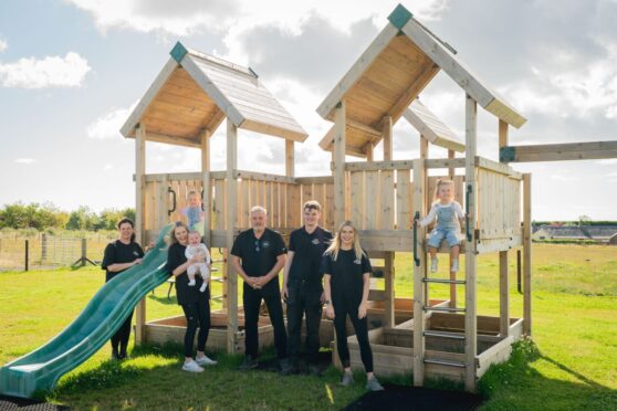 people standing in front of wooden climbing frame.