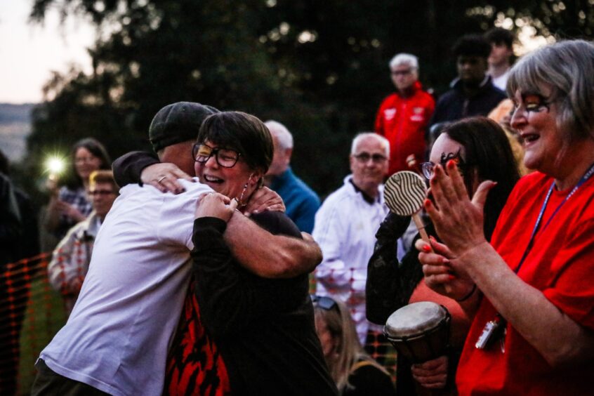 Crowd applauding while two people hug