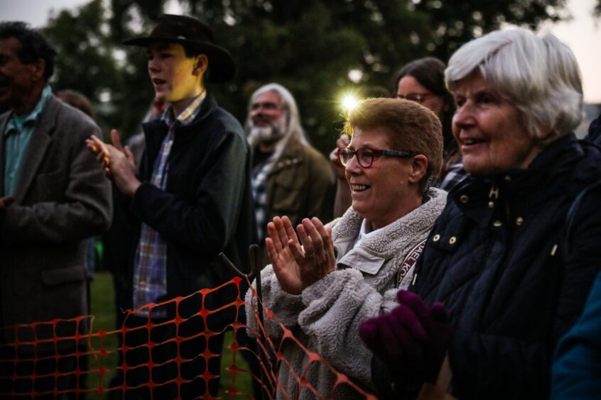 Women smiling and applauding in crowd at firewalk event