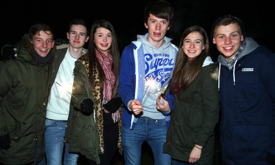 Five young people, two with sparklers, pose for a pic