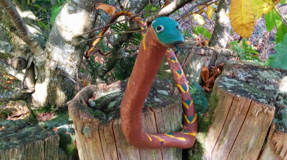 Painted wooden snake on tree trunk