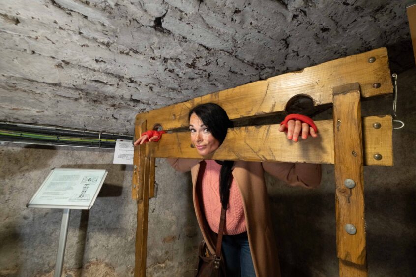 Gayle is shackled inside the pillories. 