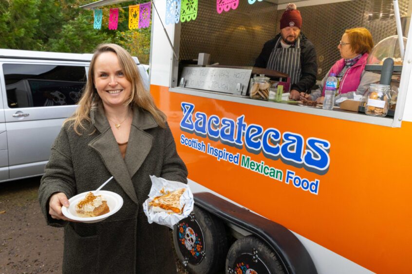 Food writer Rachel McConachie standing in front of Zacatecas food truck at Crombie Country Park, holding a quesadilla.