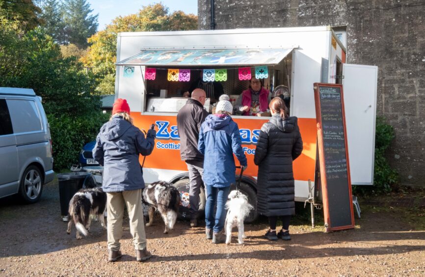 A queue of four people with their dogs outside Zacatecas food truck in Crombie Park.