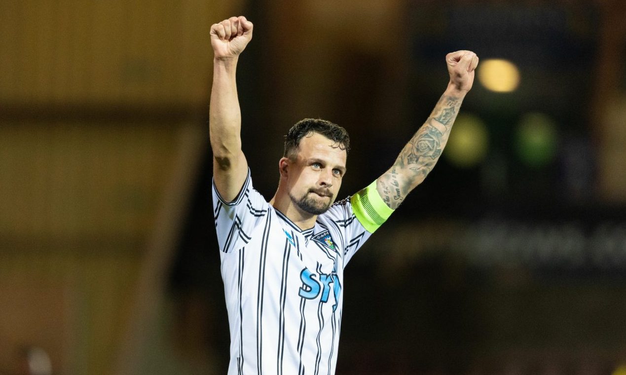 Dunfermline captain Kyle Benedictus raises both arms in the air in celebration.