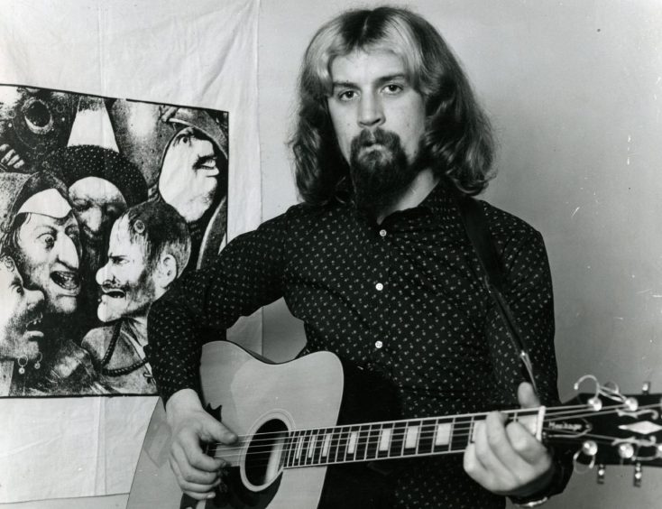 a young Billy Connolly holding a guitar