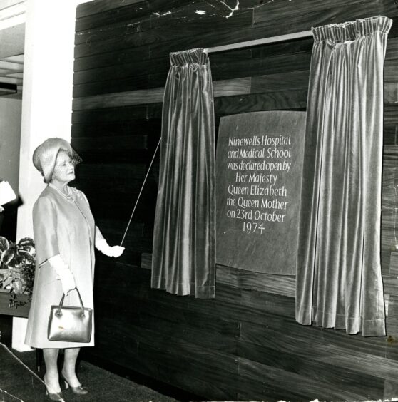 The Queen Mother drawing back the curtains on the dedication plaque.