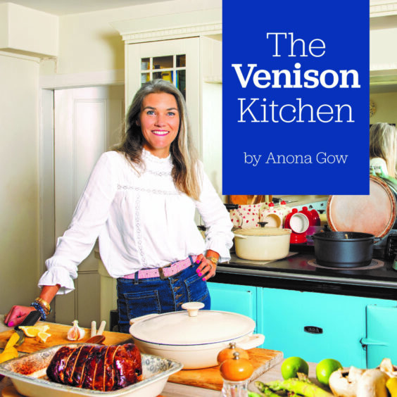 The cover of The Venison Kitchen cookbook show author Anona Gow in her farmhouse kitchen.