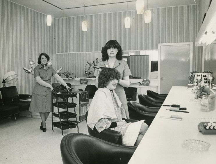 Sandi's Hair Salon with a woman getting her hair done by two hairdressers 