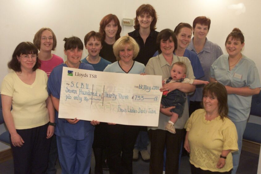 Fiona Anderson and Jackie Low from Ninewells Hospital accepting the cheque, surrounded by fundraisers