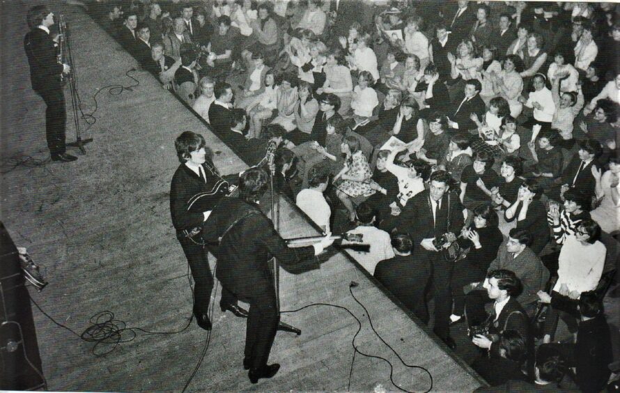 an aerial pic showing the Beatles playing as the crowd looks on