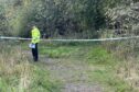 Police officer stands guard at the wooded spot in Cardenden.