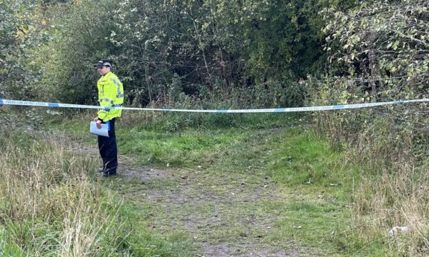 Police officer stands guard at the wooded spot in Cardenden.