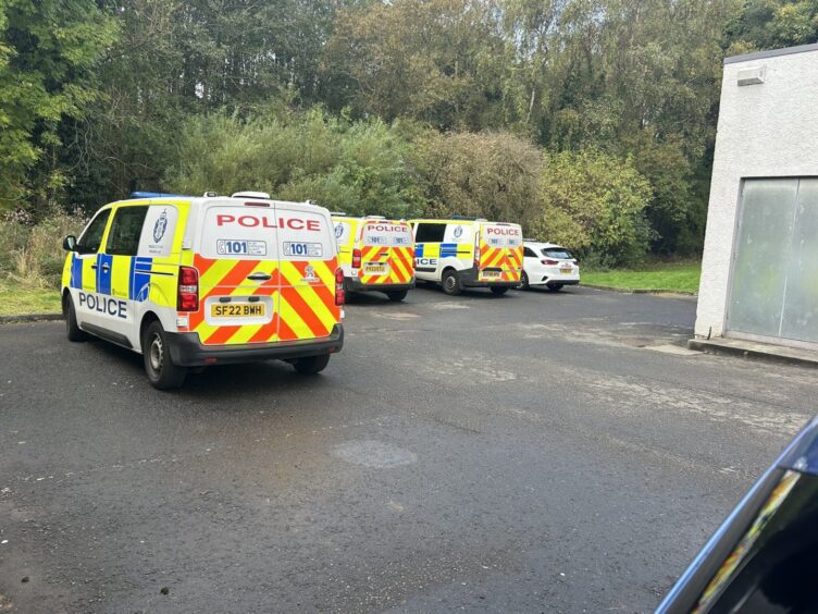 A number of police vans parked close to the woodland spot in Cardenden.