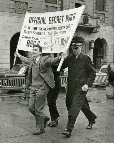 A demonstrator is led away from the rostrum by the police.