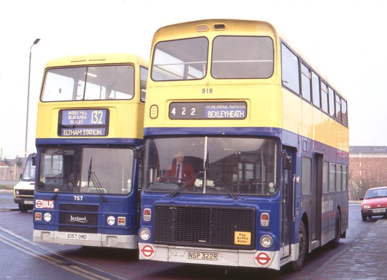 Two blue and yellow Volvo Ailsa buses