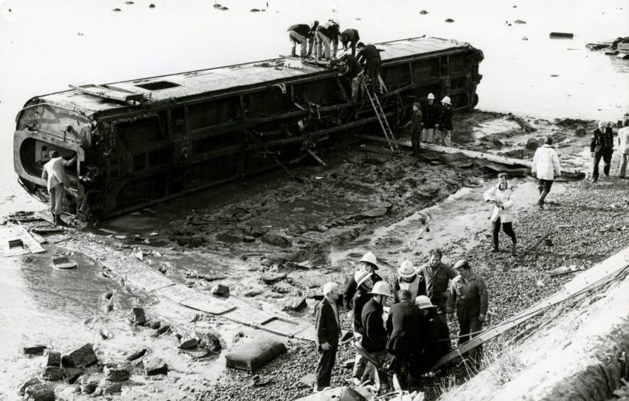 Firefighters search one of the overturned carriages after the Invergowrie rail crash. 