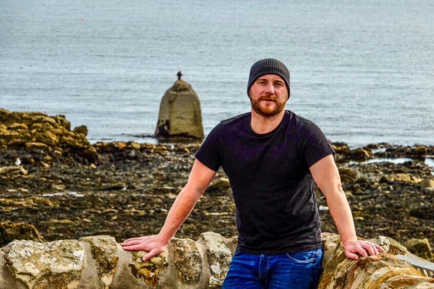 Darren Peattie sitting on a wall by the sea at St Monans.