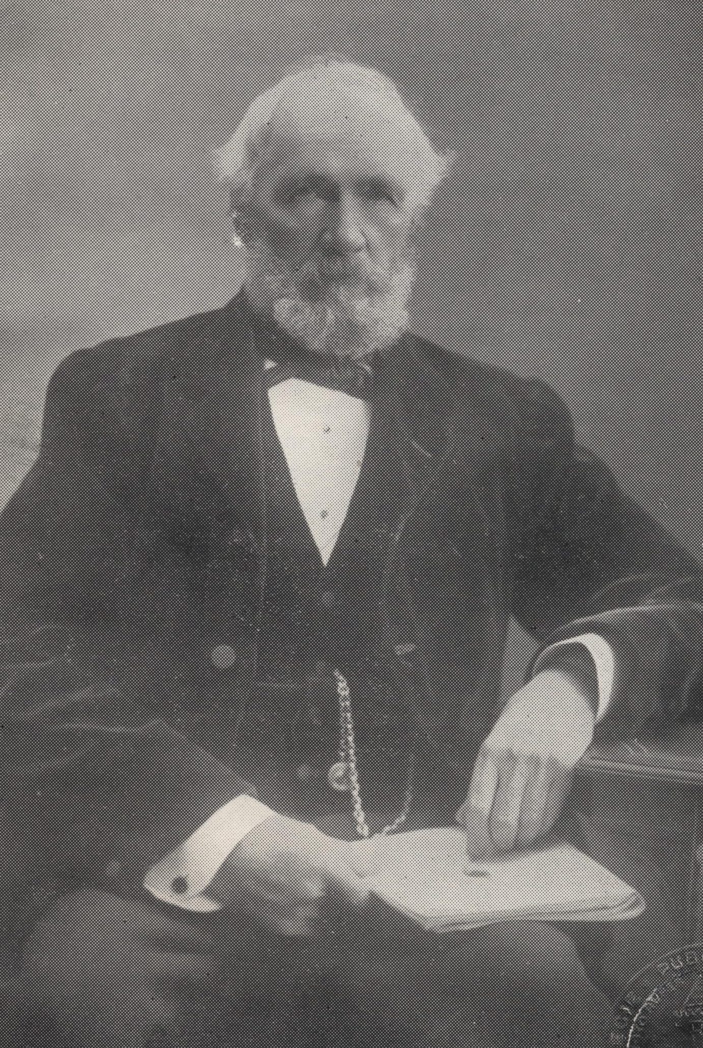 George Lauder, seated and wearing a suite and tie