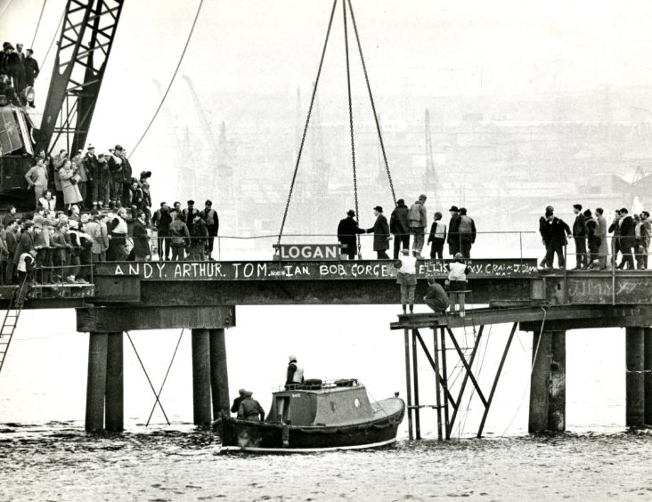 a boat sits on the water and workers stand on both sides of the bridge at the joining of he Newport and Dundee sides in 1965. 