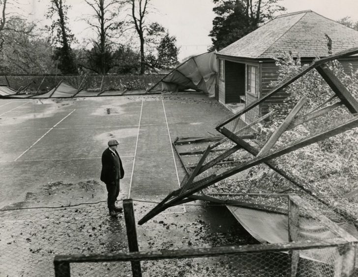 a man assessing the aftermath of the high winds, with fences blown over at Newport-on-Tay tennis court