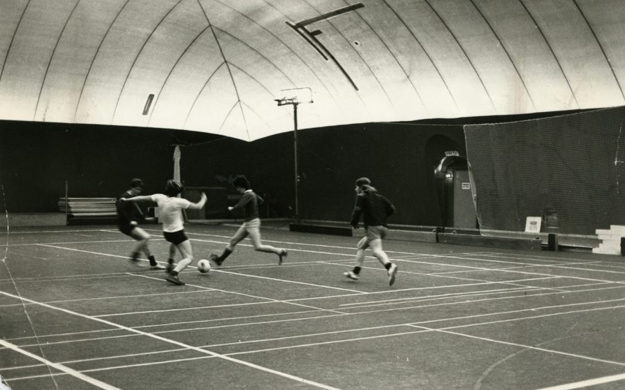 Four men play football at the sports centre 