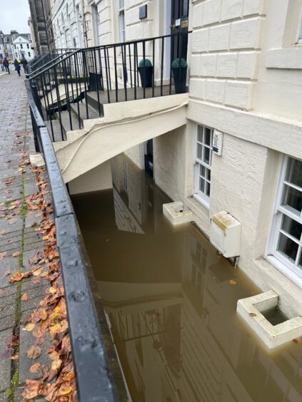 Exterior of basement property with filthy floodwater up to windows